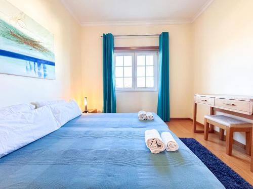 una camera da letto con un letto blu e una scrivania di Balaia Poolside House with Sea View by BeCherish a Branqueira