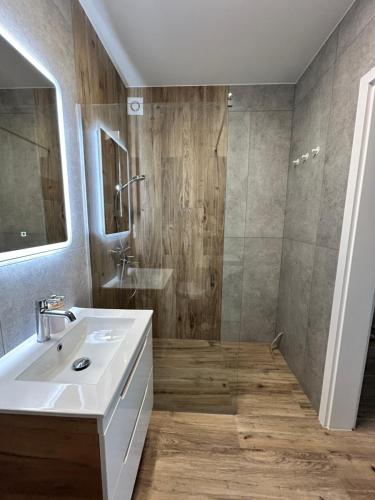 Łeba Garden Apartament في ليبا: حمام مع حوض غسيل أبيض ودش