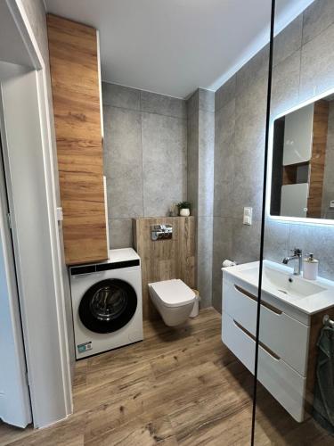 Łeba Garden Apartament في ليبا: حمام مع مرحاض وغسالة ملابس