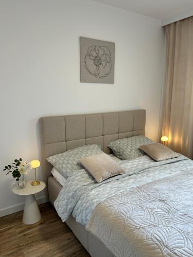 a bedroom with a large bed with pillows on it at Łeba Garden Apartament in Łeba