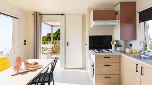 a kitchen with a table and chairs and a counter top at Camping Tikayan Saint Clair - Maeva in Moustiers-Sainte-Marie