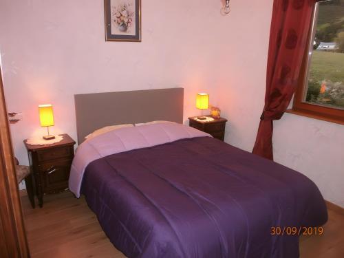 a bedroom with a purple bed with two lamps on tables at Chambre d'hôte La Châtelaine in Walbach