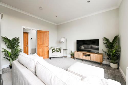 a living room with white furniture and a flat screen tv at Newly Furnished 1 Bed Flat in Wimbledon Village in London