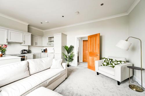 a living room with a white couch and a kitchen at Newly Furnished 1 Bed Flat in Wimbledon Village in London