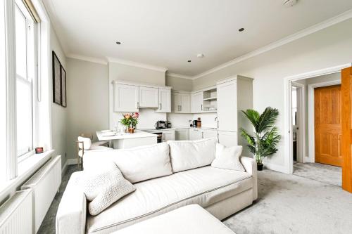 a living room with a white couch and a kitchen at Newly Furnished 1 Bed Flat in Wimbledon Village in London