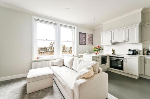a white living room with a couch and a kitchen at Newly Furnished 1 Bed Flat in Wimbledon Village in London