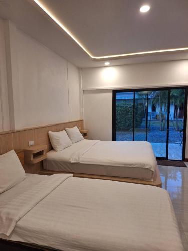 a bedroom with two beds and a large window at Lanta Mother House in Ko Lanta