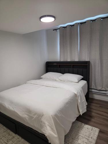 a bedroom with a large bed with white sheets at The Heavenly Crib in Saskatoon