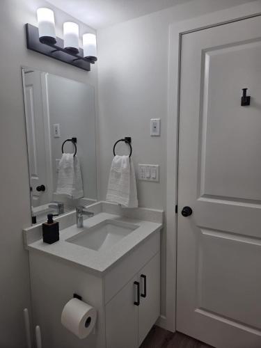 ein weißes Badezimmer mit Waschbecken und Spiegel in der Unterkunft The Heavenly Crib in Saskatoon