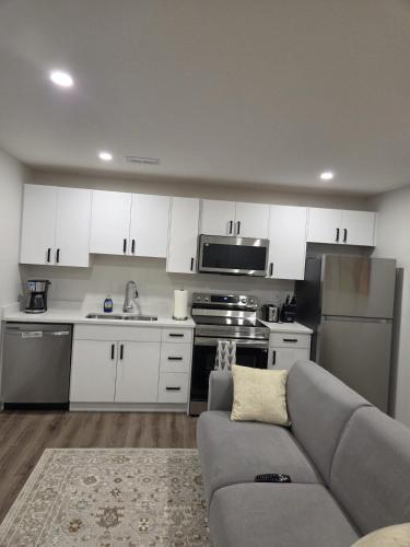a kitchen with white cabinets and a gray couch at The Heavenly Crib in Saskatoon