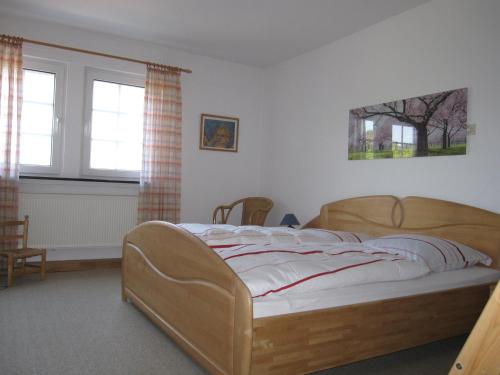 a bedroom with a wooden bed and two windows at Hof Hesse in Attendorn