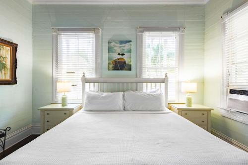 a bedroom with a white bed and two windows at Curry House - Room 5 in Key West