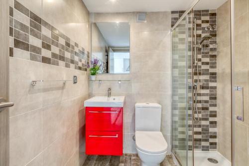 a bathroom with a toilet and a red cabinet at Estepona Real Apartamentos in Estepona