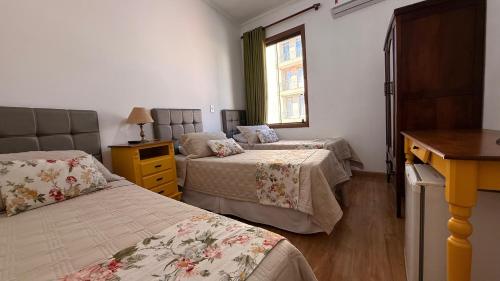 a bedroom with two beds and a window at Hotel Vitoria Marchi in Serra Negra