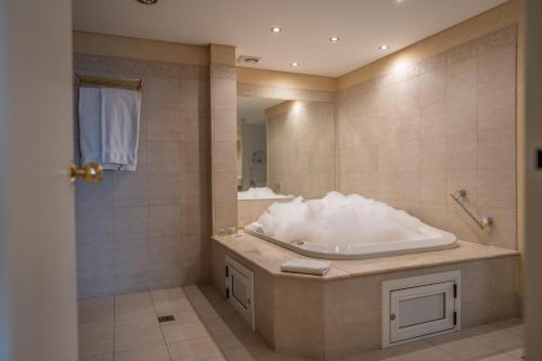 un baño con bañera y lavabo en Lucania Palazzo Hotel, en Comodoro Rivadavia