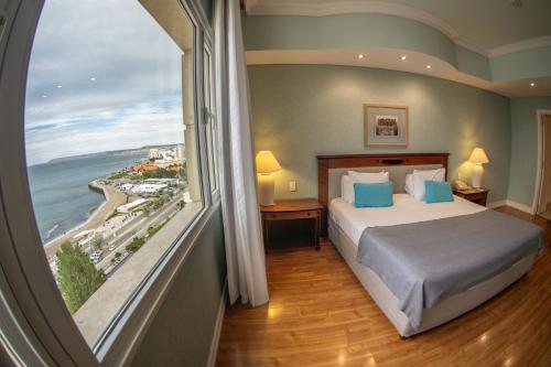 Un dormitorio con una cama y una ventana grande. en Lucania Palazzo Hotel, en Comodoro Rivadavia