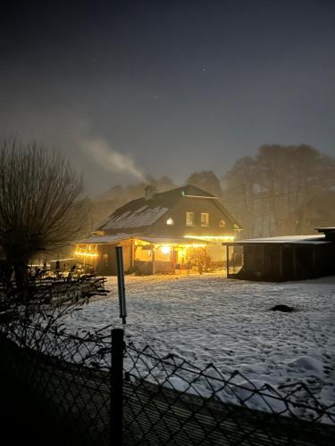 een huis bedekt met sneeuw 's nachts met lichten bij Na Zlaťáku in Malá Morava
