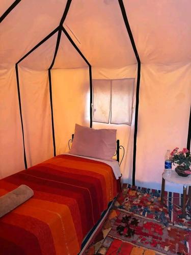 a bedroom with a bed in a tent at ERG MERZOUGA SAHARA CAMP in Merzouga