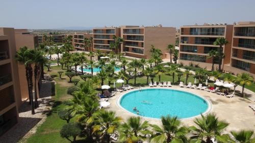 uma vista aérea de uma piscina de resort com palmeiras e edifícios em Herdade dos Salgados - Vila das Lagoas - Private Apartaments em Albufeira