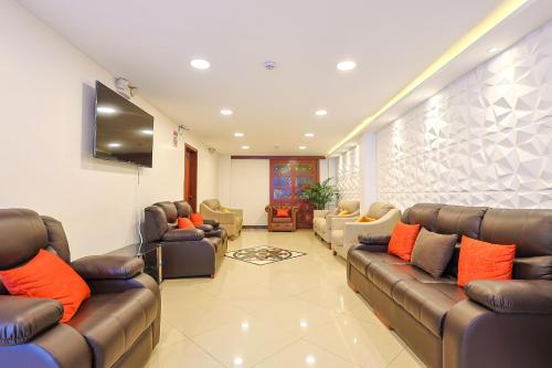 una sala de espera con sofás y TV de pantalla plana. en Hotel Quitus Airport, en Quito