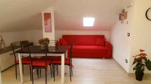 een woonkamer met een rode bank en een tafel bij Mansardina in Sanremo