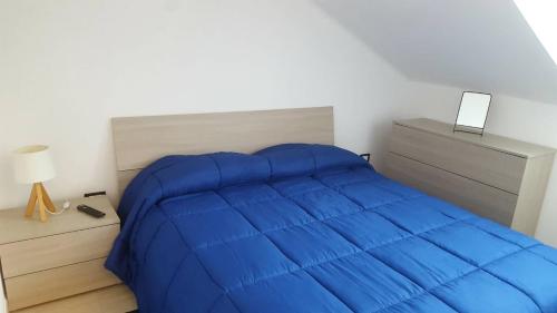 een slaapkamer met een groot blauw bed en een nachtkastje bij Mansardina in Sanremo
