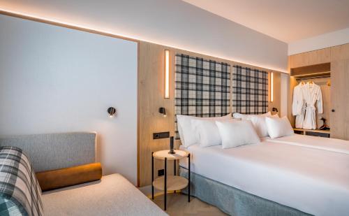 a bedroom with a large white bed and a chair at Barcelo Valladolid in Valladolid