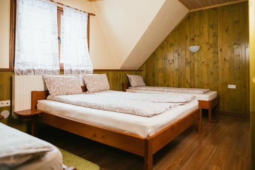 two beds in a room with wooden walls at Zafir House Harghita Bai Ski in Harghita-Băi