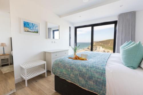 een slaapkamer met een bed met uitzicht op de oceaan bij Ocean Skies in Porthtowan