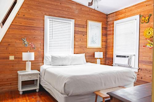 a bedroom with a white bed and wooden walls at Curry House- 3rd Floor, King Bed, & Balcony Room 8 in Key West