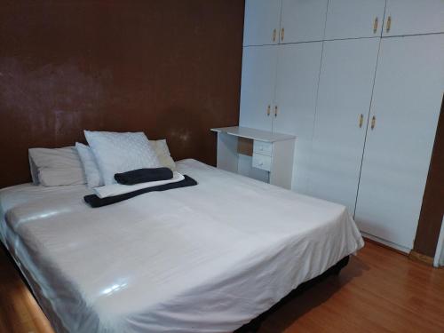 una camera da letto con letto bianco e armadi bianchi di Station Home a Città del Capo