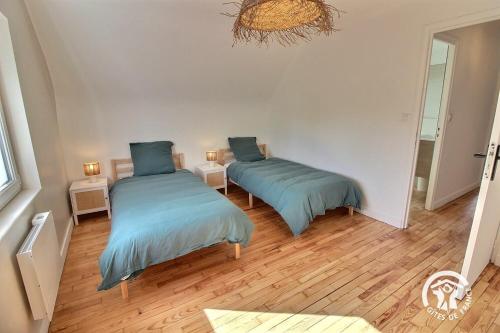 2 letti in una camera con pavimenti in legno di Ty gouldri a Perros-Guirec