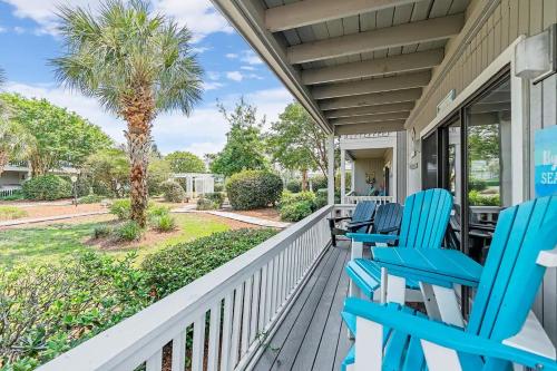 a porch with blue chairs and a palm tree at One Bedroom at Beachwood Villas on 30a in Seagrove, Florida in Santa Rosa Beach