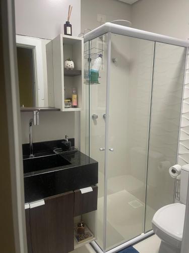 a bathroom with a glass shower and a sink at Refúgio da Luz in Capão da Canoa