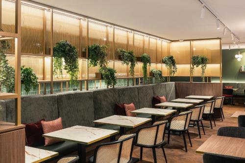 una fila de mesas en un restaurante con plantas en MAXX by Steigenberger Vienna, en Viena