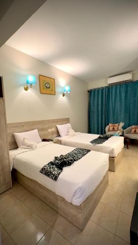 two beds in a hotel room with blue lights at Nile Hotel in Aswan