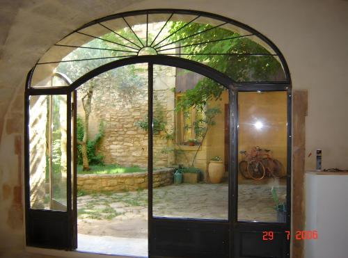 una porta a vetri ad arco con ingresso al giardino di Au Fil Des 5 Saisons a Vers-Pont-du-Gard