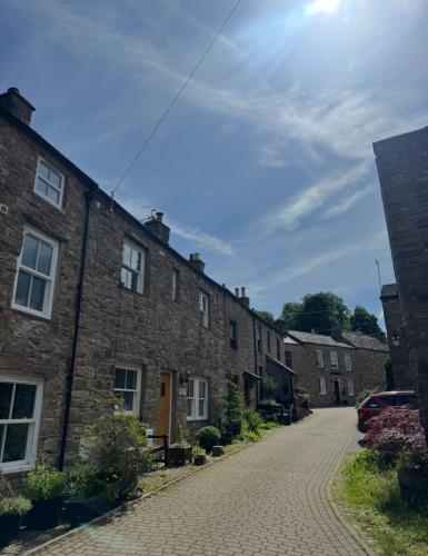 a cobblestone street in a village with stone houses at 1 Gilmore Close in Alston