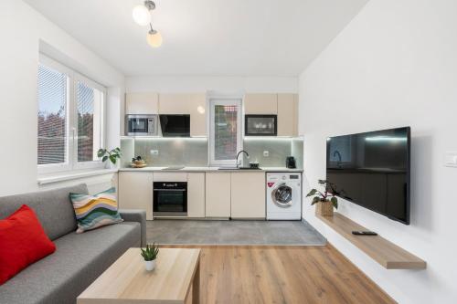 een woonkamer met een grijze bank en een keuken bij The Dante House Šeberov in Praag