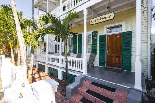 une terrasse couverte à l'avant d'une maison avec volets verts dans l'établissement Curry House - Room 9, à Key West