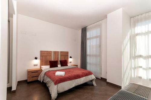 ein Schlafzimmer mit einem Bett mit einer roten Decke in der Unterkunft Palm Suites Gran Vía in Alicante