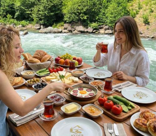 two women sitting at a table with food and drinks at Ayder Luxury Resort - Riverside Villas & Bungalows in Çamlıhemşin