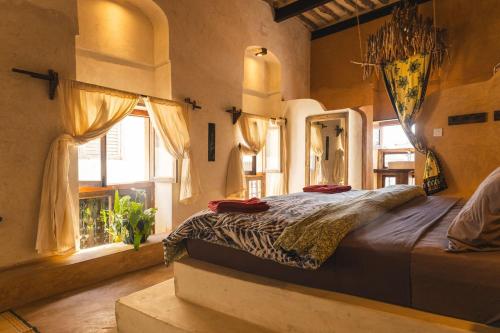 a bedroom with a large bed in a room with windows at Firefly boutique Hotel Zanzibar in Zanzibar City