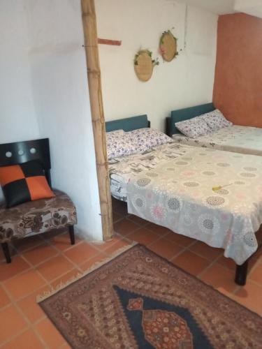 Hostal ROLLED في فيلافيجا: سريرين في غرفة بها كرسي وسجادة