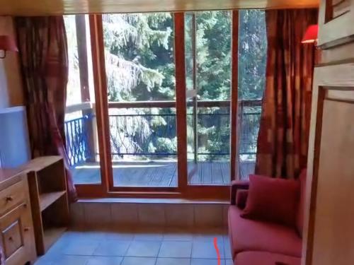 Cosy Duplex Arc1800 Aiguille Grive1 6 personnes في آرك 1800: غرفة معيشة مع نافذة كبيرة وكرسي