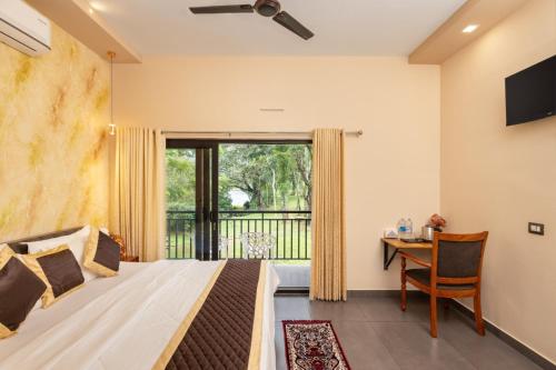 a bedroom with a bed and a desk and a window at Vipinam, The riverside retreat in Kotamangalam