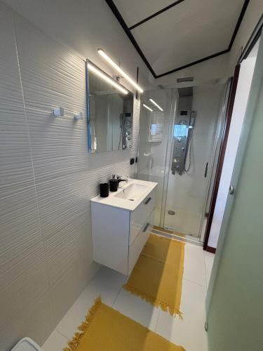 a white bathroom with a sink and a shower at Villa delle torri in Pula
