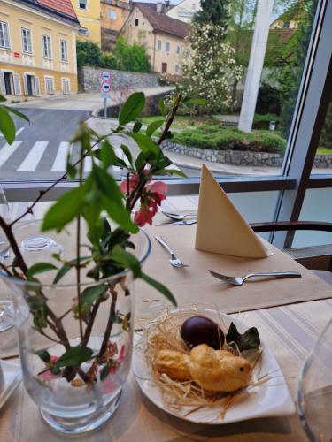 una mesa con un plato de comida y un jarrón con una planta en Hotel Bela Krajina, en Metlika