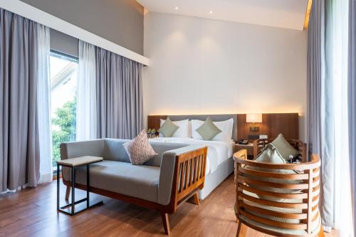 a bedroom with a bed and a couch and a chair at Wyndham Garden Jim Corbett Chhoi in Belparāo