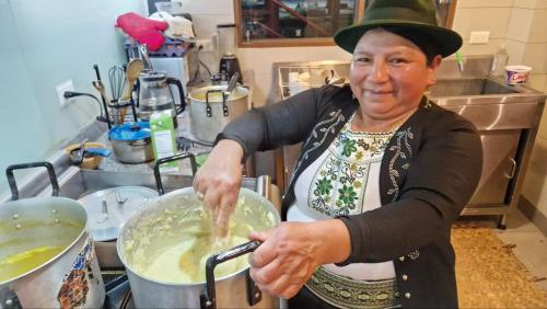 a woman in a kitchen stirring a pot of food at La Maison d'Urbina in Chimborazo